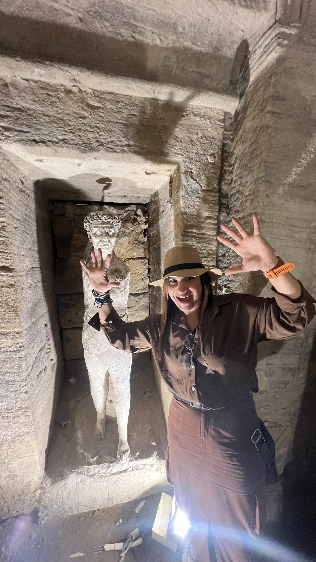 Visitor beside ancient carved figures in the Catacombs of Kom el Shoqafa