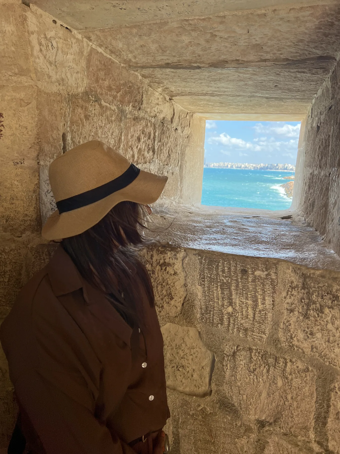 Visitor looking at the Mediterranean Sea through a window at the Citadel of Qaitbay